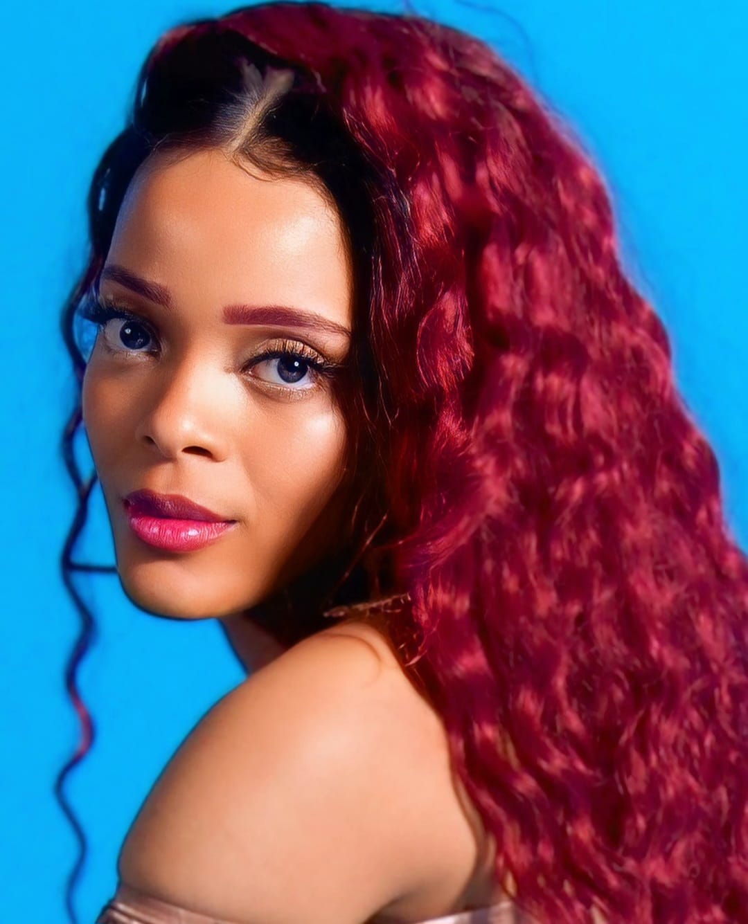AlxZandria portrait with crimson curls against a blue backdrop